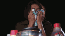 a woman covering her face with a towel with a face on it that says ' doraemon ' on it