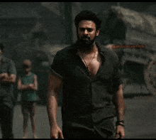 a man with a beard wearing a black shirt and a necklace stands in front of a wagon