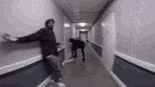 a man is standing in a hallway with his arms outstretched while another man stands behind him .