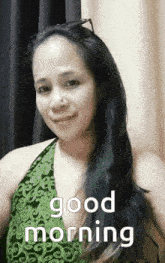 a woman in a green dress is smiling and says good morning