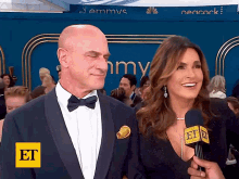 a man in a tuxedo is being interviewed by a woman in a black dress