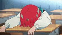 a girl with red hair laying her head on a desk in a classroom