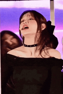 a woman in a black off the shoulder top with a choker on her neck