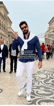 a man wearing a blue shirt and white pants is standing in front of a building