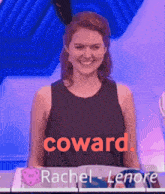 a woman in a black tank top with the word coward written on it