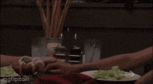 a couple holding hands over a table with a plate of food .