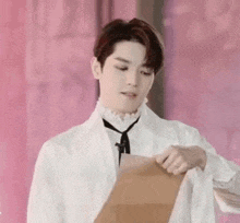 a man in a white shirt and tie is holding a piece of paper in his hand .