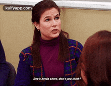 a woman in a purple sweater is talking to another woman in a classroom .