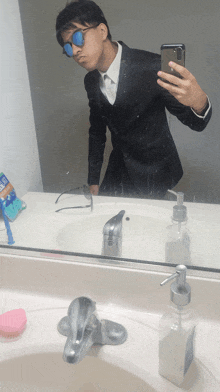 a man in a suit taking a selfie in a bathroom