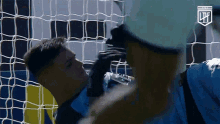 a man in a blue shirt is standing in front of a soccer net with the letters lpf on the bottom