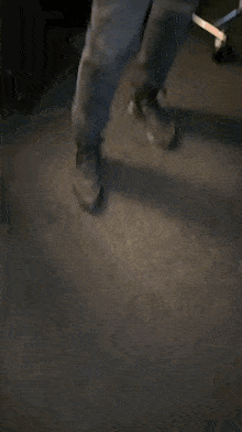 a man in a blue jacket and gray pants is standing on a dark floor .