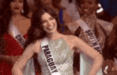 a woman wearing a sash that says paraguay is smiling while standing in front of other women .