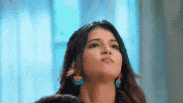 a woman wearing earrings is looking up at the sky .
