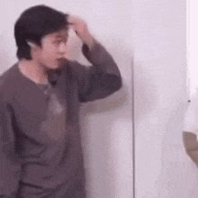 a man is standing in front of a wall and brushing his hair .