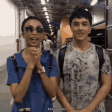 a man and a woman are standing next to each other in a hallway with the word mayward on the bottom right