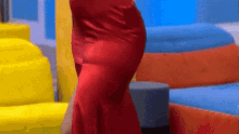 a woman in a red dress is standing in a room with yellow and blue chairs .
