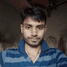 a man with a beard wearing a blue and grey striped shirt takes a selfie