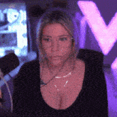 a woman wearing glasses and a black shirt is sitting in front of a microphone in a dark room .