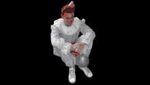 a man dressed as a clown with blood on his face is sitting down