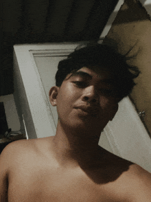 a shirtless man is taking a selfie in front of a white door