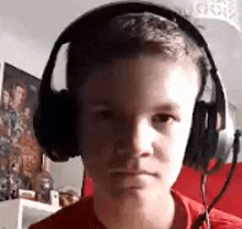 a young boy wearing headphones is looking at the camera in a room .