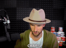 a man wearing a hat says crap while standing in front of a microphone