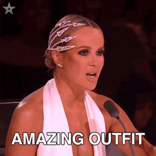 a woman in a white dress is speaking into a microphone with the words amazing outfit below her