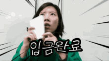 a woman in a green jacket is holding a piece of paper in her hand