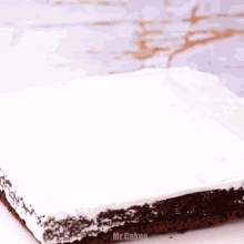 a bottle of chocolate frosting is being poured on a brownie