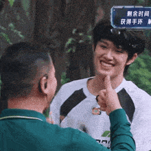 a man giving a thumbs up to another man with chinese writing on the screen behind him