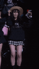 a girl wearing a straw hat and a plaid skirt