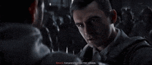 a man is talking to another man in front of a crowd of people .