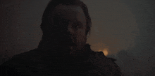 a man with a beard is standing in a dark room looking at the camera .