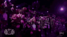 a bunch of flowers in a dark room with a mercedes logo in the background