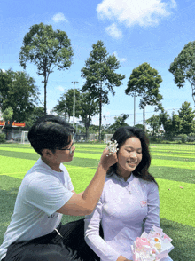 a man putting flowers on a woman 's ear while she holds a bouquet