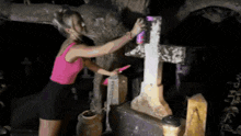 a woman in a pink tank top is cleaning a cross with a brush