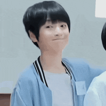 a boy with short black hair is wearing a light blue jacket