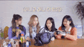 a group of girls are sitting at a table looking at a purse with korean writing on the top