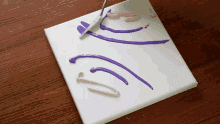 a white canvas with purple and pink paint being applied to it