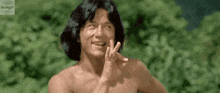 a shirtless man is making a peace sign with his hands .