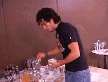 a man in a black shirt is pouring something into a mug