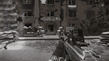a person holding a gun in front of a building with welcome to hell written on it