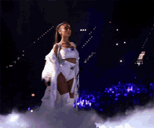 a woman in a white outfit is walking on a stage with a microphone