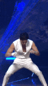 a man in a white jumpsuit is dancing on a stage in front of a microphone .