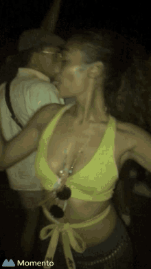 a woman in a yellow crop top is dancing with a man in a hat and the word momento is on the bottom left