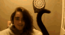 a woman is standing in front of a dart board with a cat behind her .