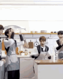 a group of people are standing in a kitchen .