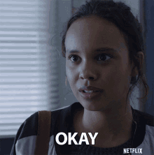 a netflix ad shows a girl with a ponytail and the word okay on her face