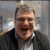 a man wearing glasses is laughing with his mouth wide open