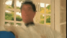 a blurry picture of a man standing in front of a window with his eyes closed .